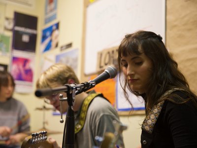 Lauren of Bellflower sits facing the mic as Eric and Phoebe are in the foreground
