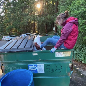 Student cramming items into a dumpster