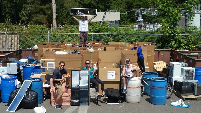Students posing around large cardboard boxes of clothes, mirrors and assorted household items.