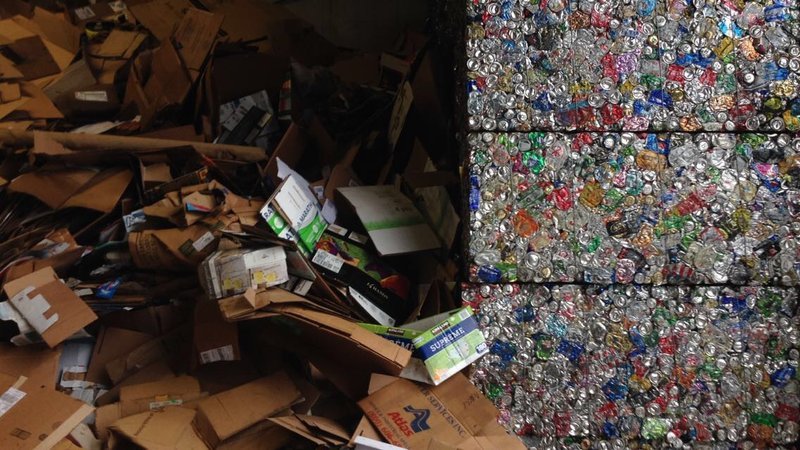 Loose cardboard next to crushed blocks of aluminum cans