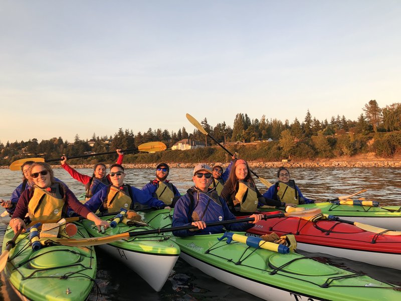 Group of students sea kayaking with red and green boats
