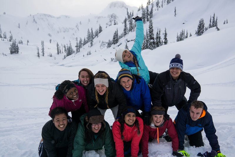 Group of smiling students making a human pyramid in the snow
