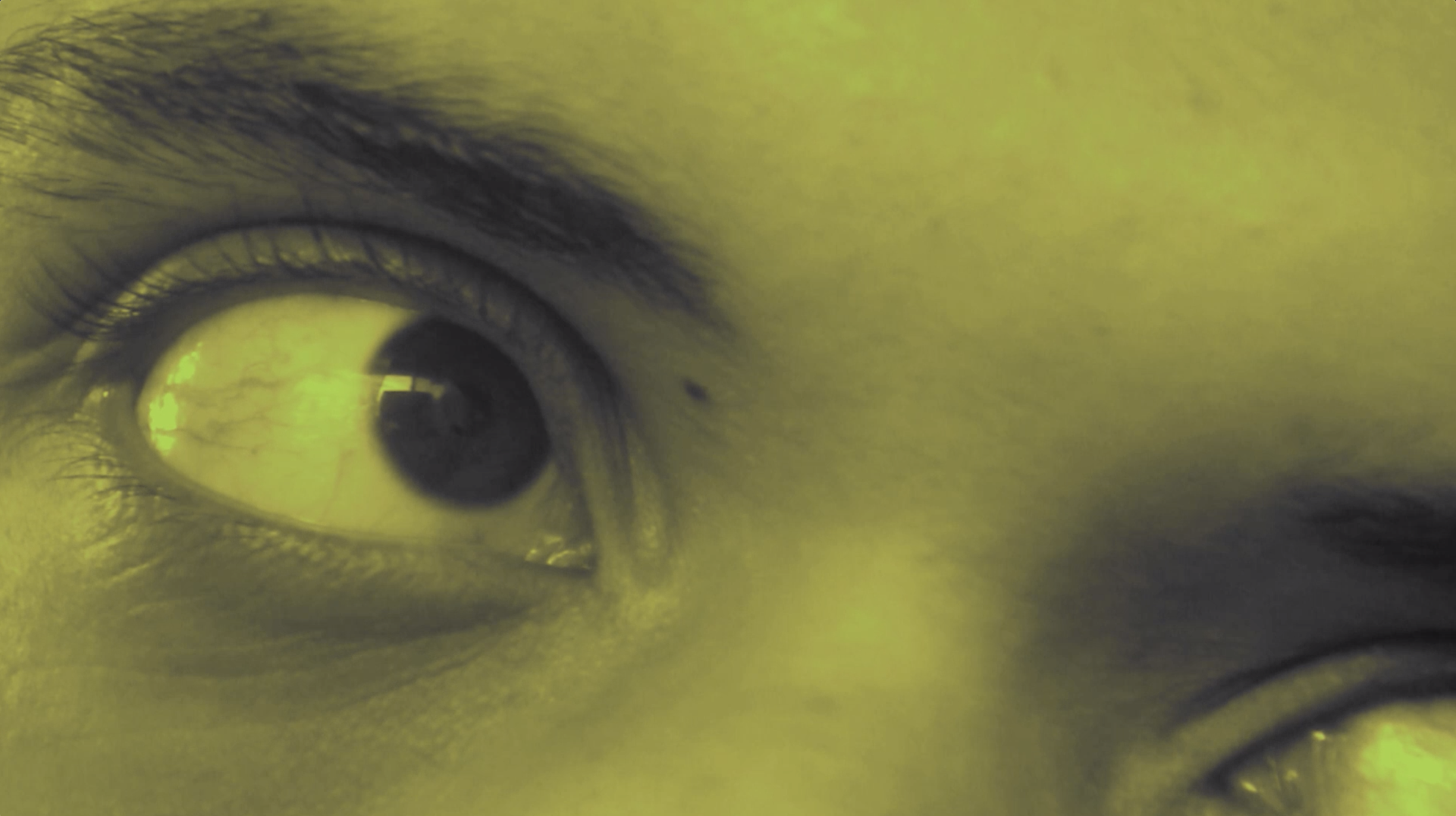 Screen capture of a digital short film which shows a green toned closeup shot of the actor's eyes