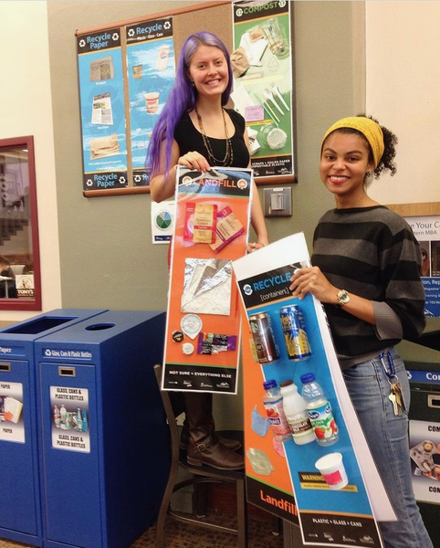 Previous zero waste coordinators hanging waste sorting signs in Zoe's Market