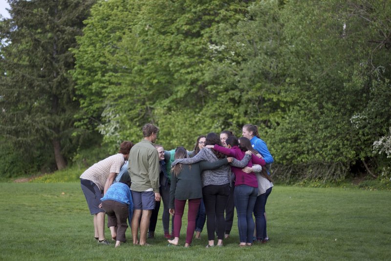 Group of students gathered closely together in a huddle in a grassy field
