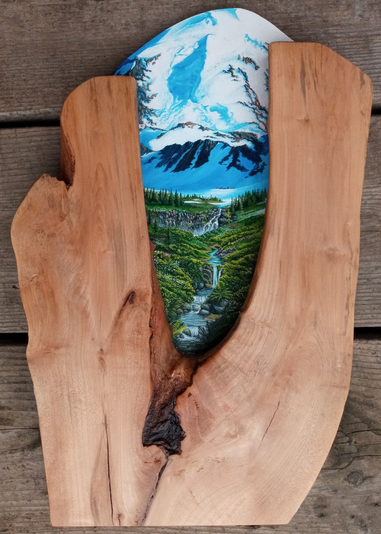 rounded painting of a stream and snowy mountains inlaid in a wooden frame